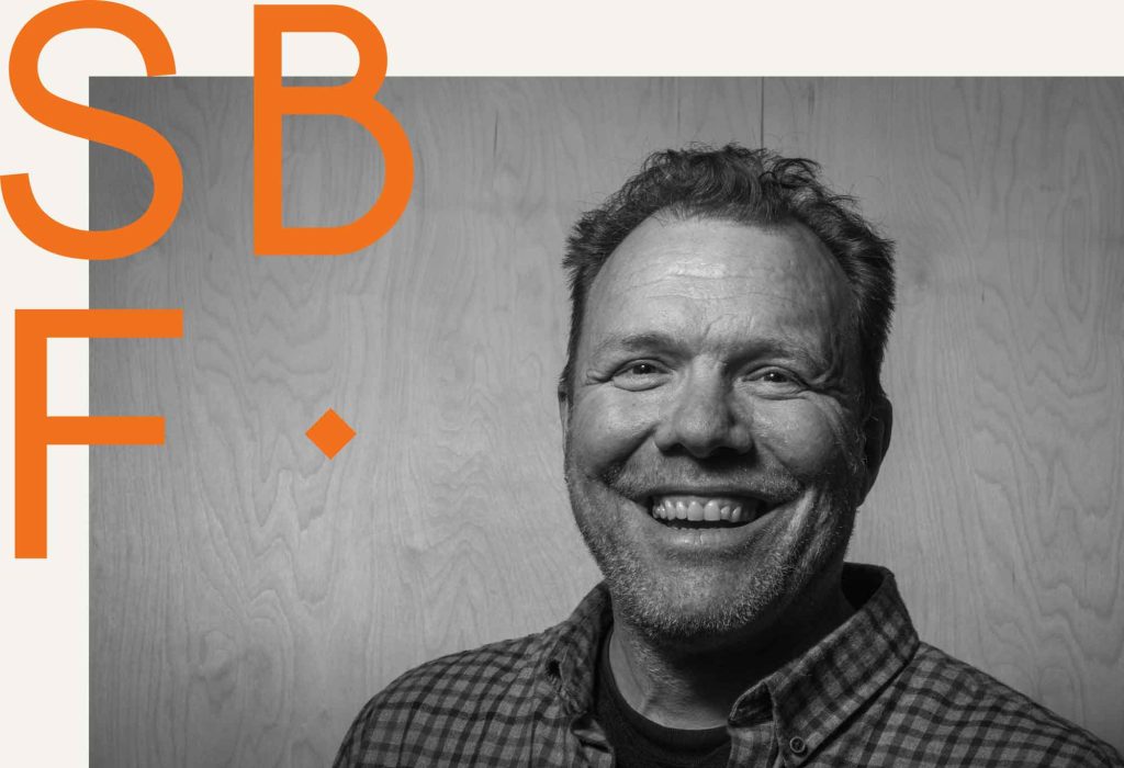 A black and white photo of our founder Marc Ellis with the SBF logo